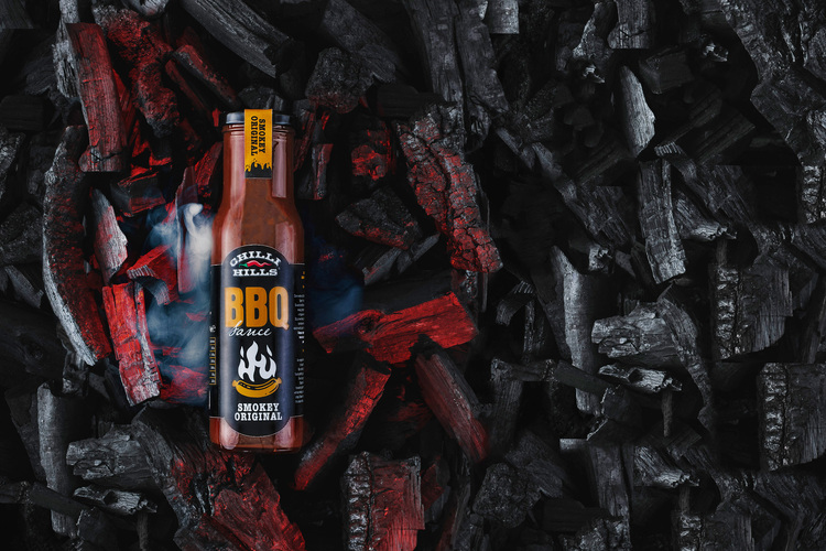 Ketchup BBQ Chilli Hills Bottle On the coals. Ketchup BBQ Chilli Hills Bottle On the coals. Ketchup BBQ Chilli Hills Bottle is on the coals. Around the can of ketchup itself, the coals are bright red, they are red-hot and hot! This tells the viewer that the ketchup is very spicy!