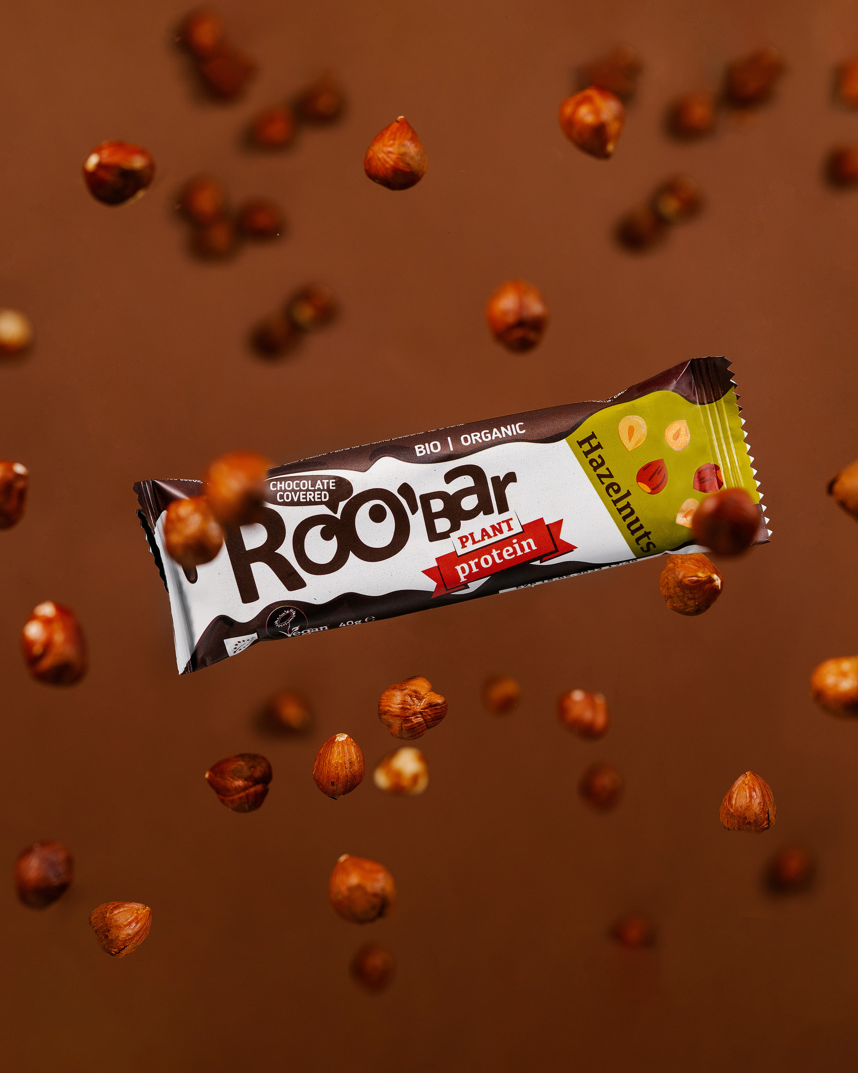 Protein bar Roobar with hazelnuts. Protein bar Roobar in free flies among nuts hazelnuts. On the brown background.