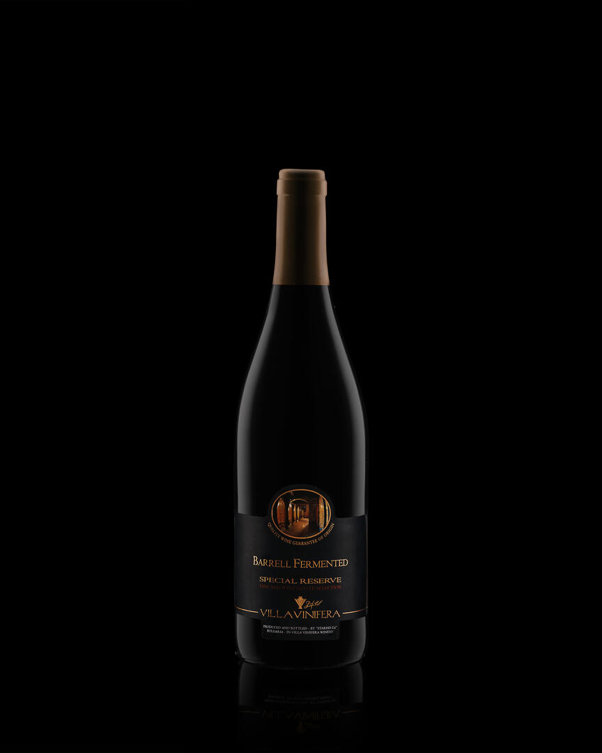 A bottle of Barrell Fermented Special Reserve wine Villa Vinifera on a dark background. A bottle of Barrell Fermented Special Reserve wine Villa Vinifera on a dark background with soft highlights in the shape of the bottle. Reflection is located at the bottom of the bottle.